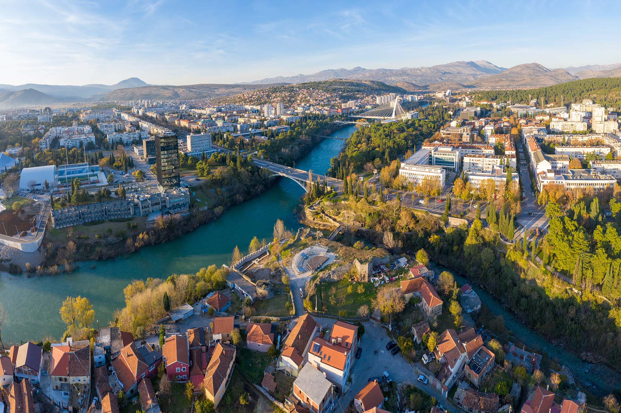 Confluence of Ribnica and turquoise Moraca river, flowing through downtown Podgorica in Montenegro on a sunny afternoon. Old town (Stara Varos) with red roofs.