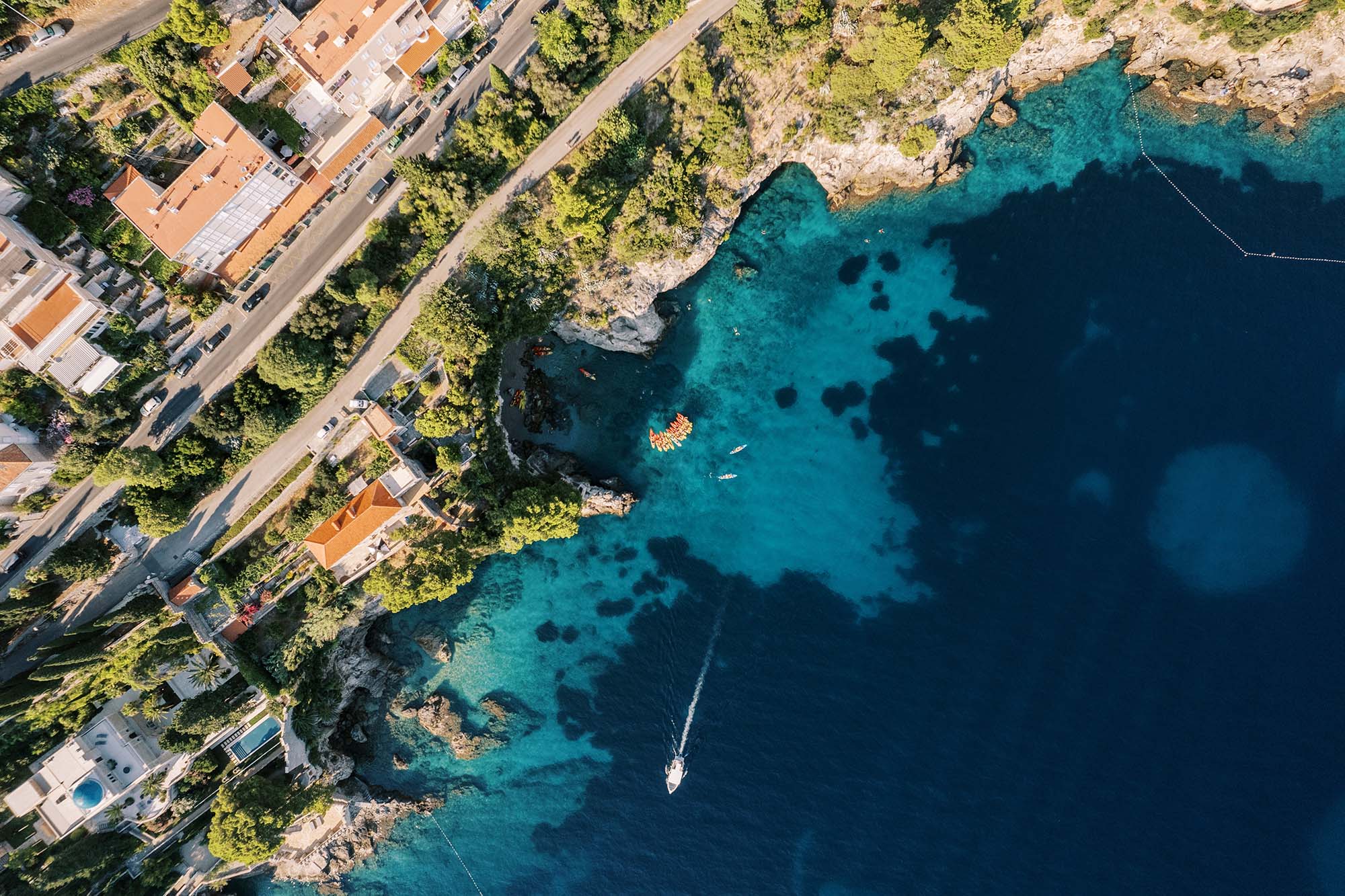 Row of colorful boats sits in a bay off the green coast of Dubrovnik. Croatia. Top view